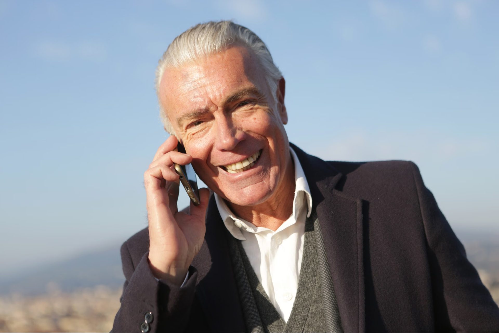 A smiling retired man talking on the phone outdoors