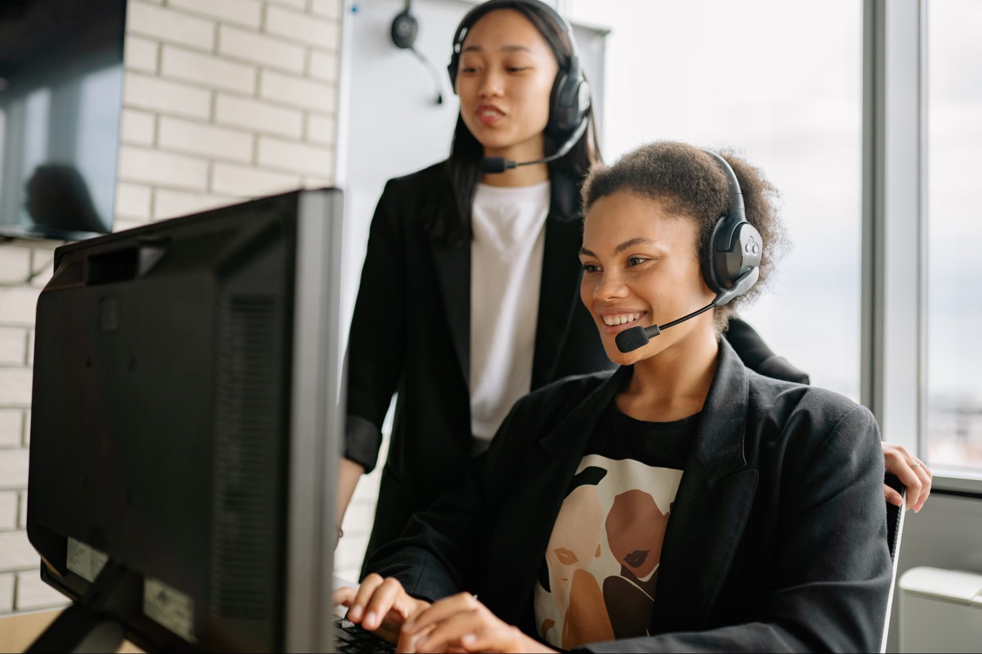Two smiling support specialists wearing headsets
